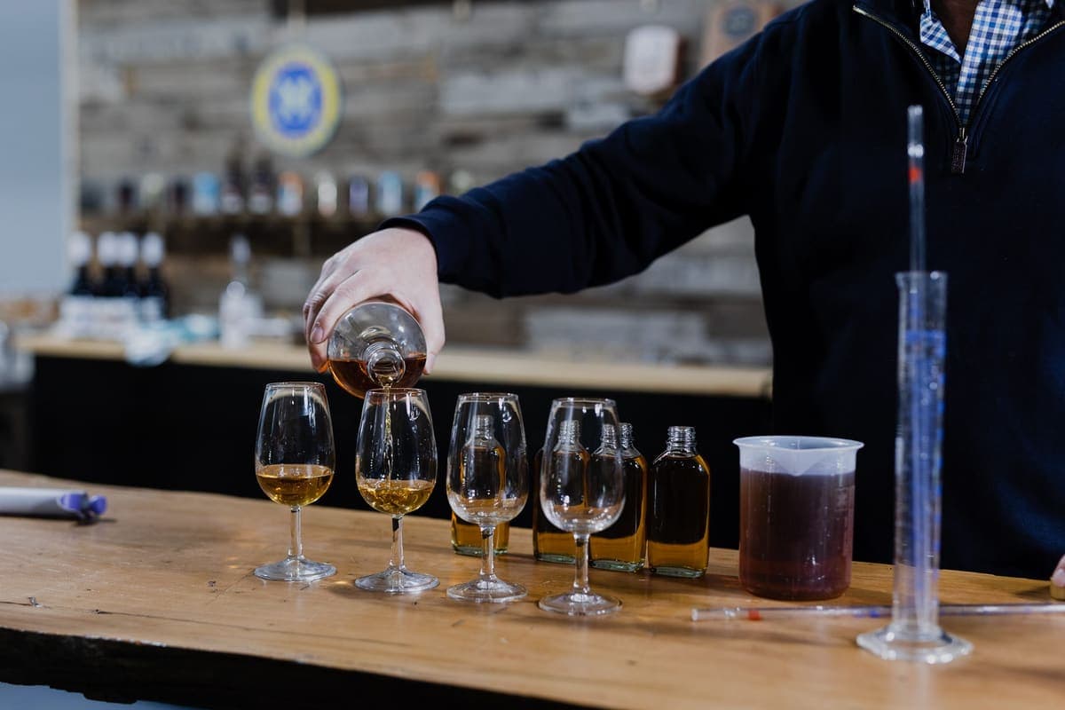 Distiller pouring a tasting flight of 78 Degrees spirits across the bar